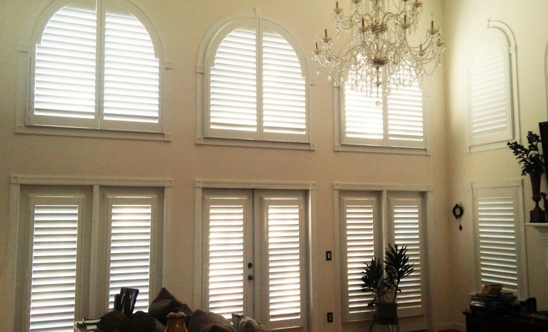 Entertainment room in two-story Cincinnati house with plantation shutters on high ceiling windows.