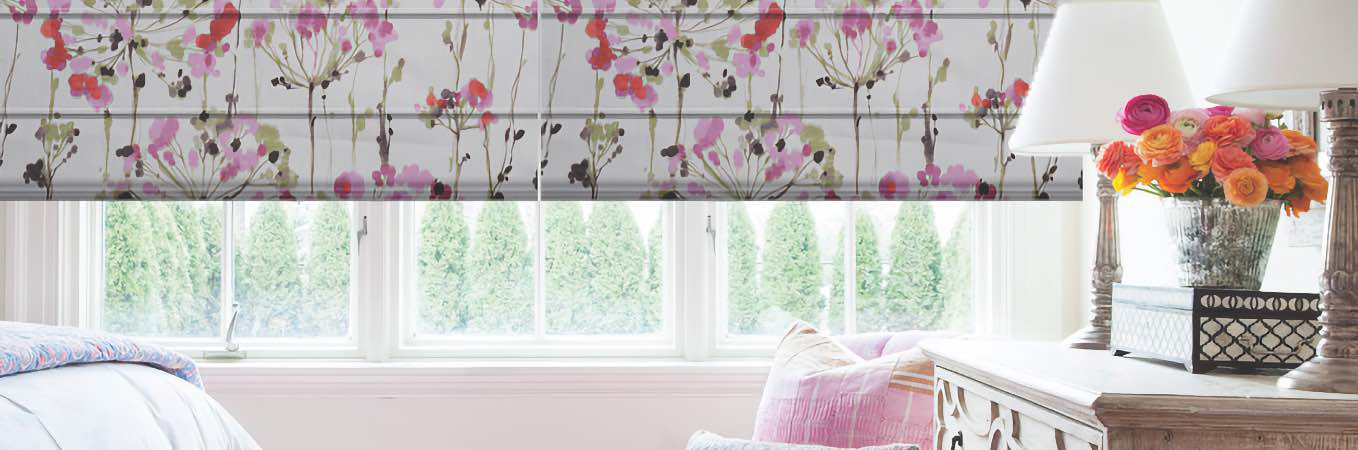 Pink patterned window shades and other accents in a white room