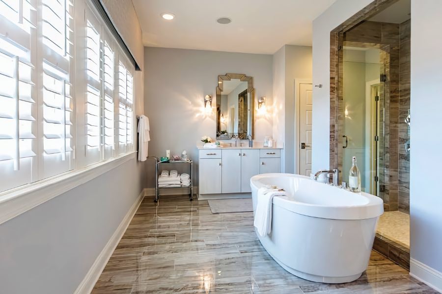 Stylish bathroom with plantation shutters, distinctive flooring, and free-standing tub.