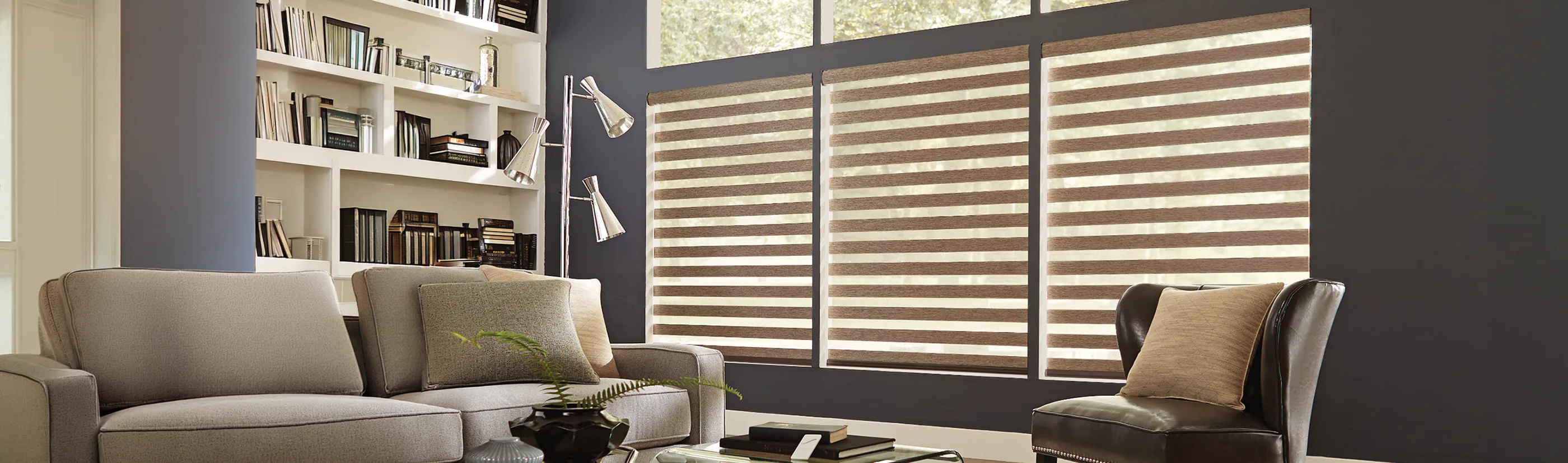 Beige transitional shades in three medium sized windows in a modern decorated living room