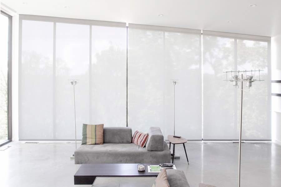 Motorized window shades make controlling natural light effortless in your Cincinnati great room. White motorized shades on a wall of tall great room windows