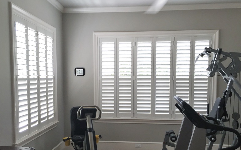 Draft-blocking window treatments are vital in rooms with windows on more than one wall. Cincinnati exercise room with shuttered windows.