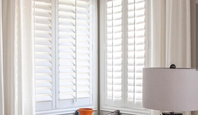 Plantation shutters offer an elegant look and superior method of directing natural light to reduce glare. Plantation shutters in a corner window.