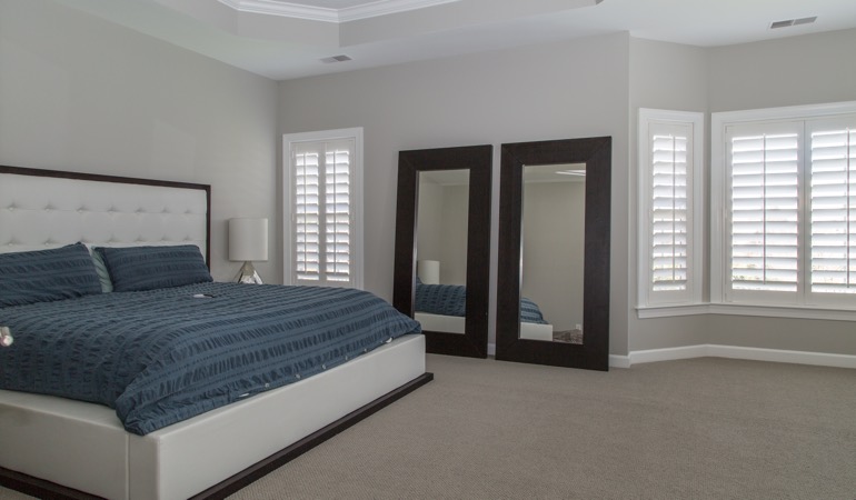Polywood plantation shutters combine form and function. White shutters in a minimalist bedroom in Cincinnati.