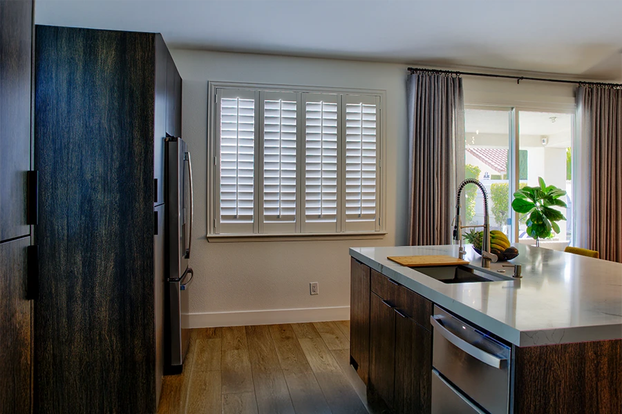 Higher-quality shutters may cost more, but they're well worth it! White Polywood shutters on a kitchen window
